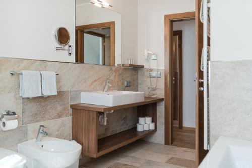 a bathroom with a sink and a toilet and a mirror at Apartmenthaus Gruberhof in Schenna