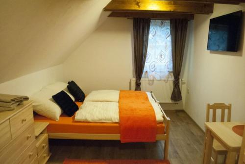 ein Schlafzimmer mit einem Bett mit einer orangefarbenen Decke und einem Fenster in der Unterkunft Apartmany Silverado in Horní Bečva