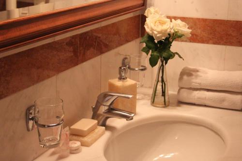a bathroom sink with a vase of flowers on it at Achillion Hotel in Athens