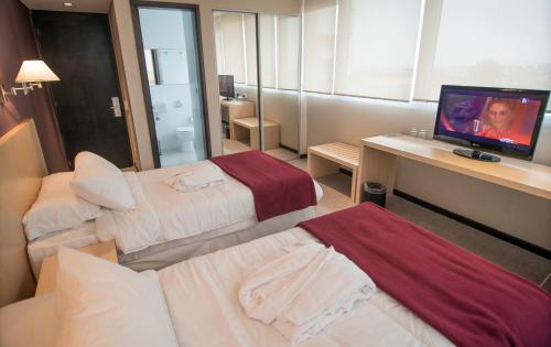 a hotel room with two beds and a desk with a television at Salto Hotel y Casino in Salto