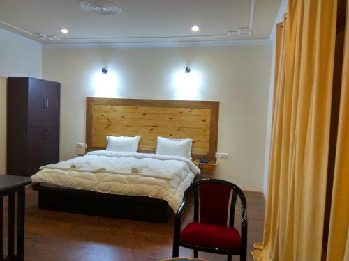 a bedroom with a large bed and a red chair at Shaolin Ladakh in Leh