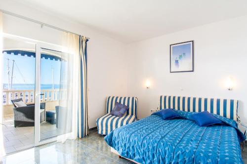a bedroom with a bed and a chair and a balcony at Apartments Duje in Dugi Rat