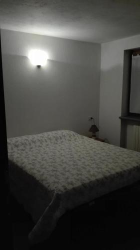a bed in a bedroom with a light on the wall at Hygge Chalet a Champoluc in Champoluc