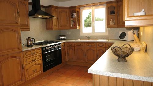 La cuisine est équipée de placards en bois et d'une cuisinière noire. dans l'établissement Les Lavandes, à Étaules