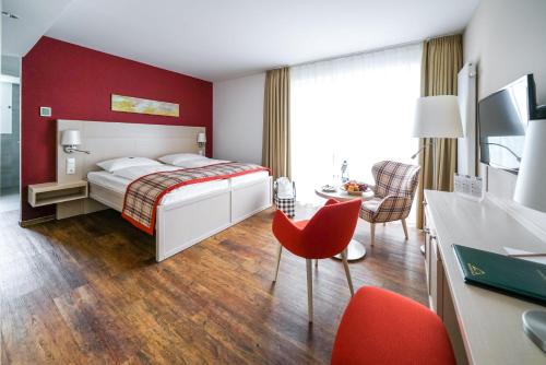 une chambre d'hôtel avec un lit, une table et des chaises dans l'établissement Ringhotel Warnemünder Hof, à Warnemünde