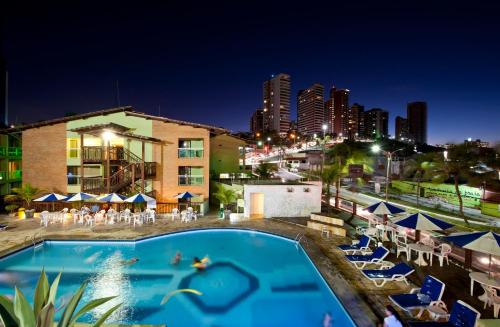 a pool at night with a city skyline in the background at Natal Praia Hotel in Natal