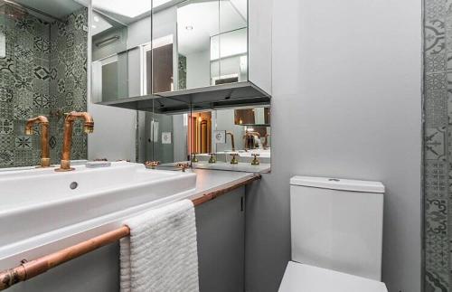 een badkamer met een wastafel, een toilet en een spiegel bij Unique Studio House | City Centre in Lissabon
