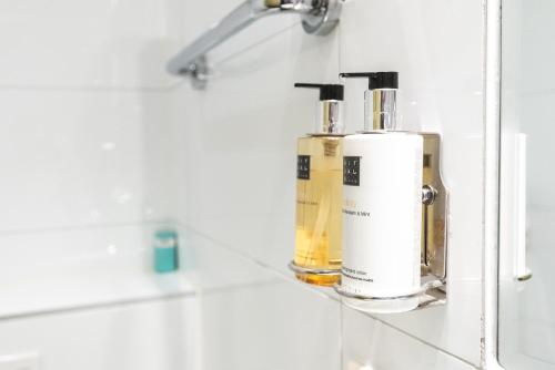 dos botellas de odorizantes sentadas en un estante en un baño en Hotel Hoksbergen, en Ámsterdam