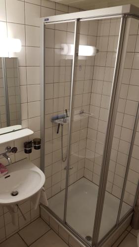 a shower with a glass door next to a sink at Hotel Lötschberg in Spiez