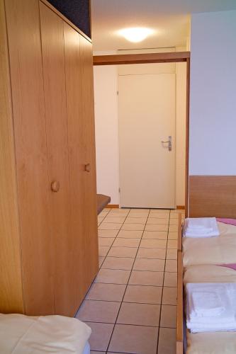a room with three beds and a door at Hotel Lötschberg in Spiez