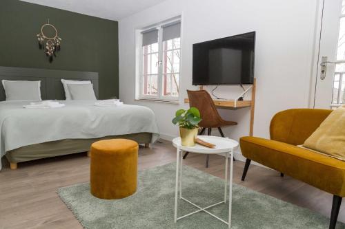 a bedroom with a bed and a tv and a couch at Hotel - Restaurant De 4 Jaargetijden in Epen
