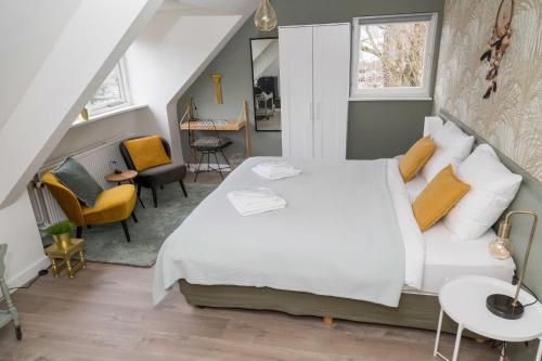 a bedroom with a large white bed and chairs at Hotel - Restaurant De 4 Jaargetijden in Epen