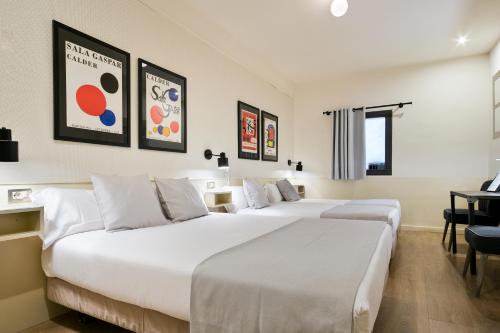 Una habitación de hotel con dos camas y un escritorio. en Hotel El Call, en Barcelona