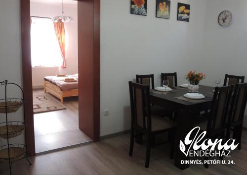 a dining room with a table and a room with a bed at Ilona vendégház Dinnyés in Dinnyés