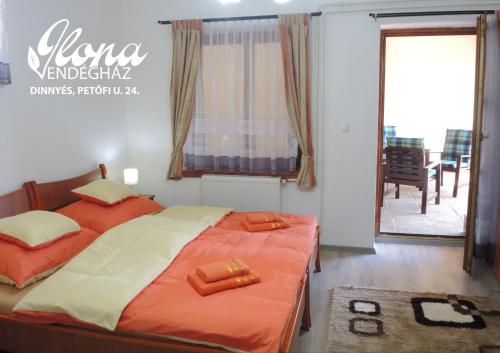 Schlafzimmer mit einem Bett mit orangefarbener Bettwäsche und einem Balkon in der Unterkunft Ilona vendégház Dinnyés in Dinnyés