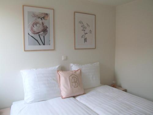 ein Schlafzimmer mit einem weißen Bett und einem rosa Kissen in der Unterkunft Maison HB in Ypern