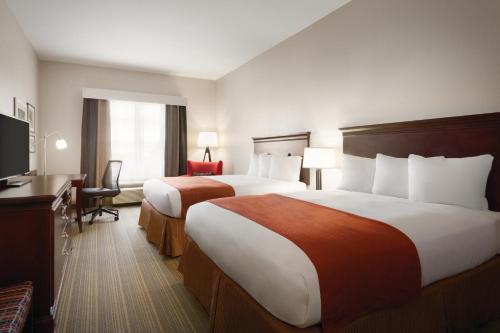 um quarto de hotel com duas camas e uma televisão de ecrã plano em Country Inn & Suites by Radisson, St Petersburg - Clearwater, FL em Pinellas Park