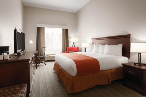 a hotel room with a large bed and a desk at Country Inn & Suites by Radisson, St Petersburg - Clearwater, FL in Pinellas Park