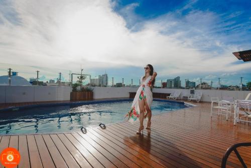 a woman in a dress standing next to a swimming pool at Hotel Arenal in Santa Cruz de la Sierra