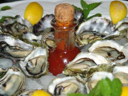 a plate of oysters with a bottle of sauce at Riverside Homestead in Paihia