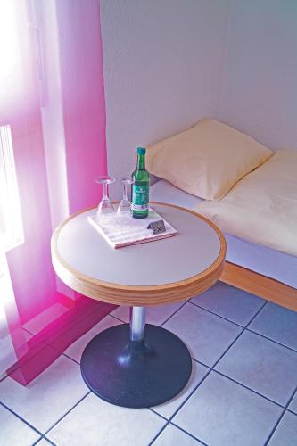 Una pequeña mesa con dos vasos y una botella. en Hotel Lötschberg en Spiez