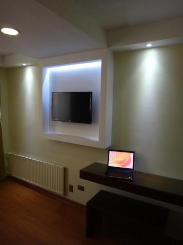 a room with a laptop on a wall with a flat screen tv at Hotel Libertador in Santiago