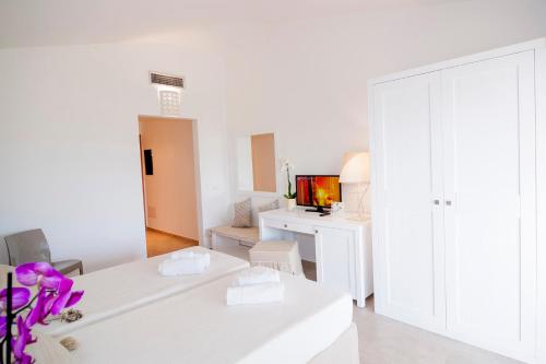 a white living room with a white couch and a tv at Stella Marina Budoni in Budoni