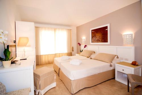 a bedroom with two beds and a desk in it at Stella Marina Budoni in Budoni
