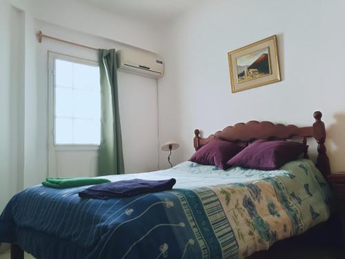 Un dormitorio con una cama con almohadas moradas y una ventana en Departamento Alvarado en Salta
