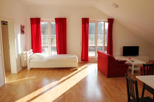 メッヒャーニッヒにあるFerienwohungen - Apartments Satzveyの赤いカーテン、ベッド1台、ソファが備わります。
