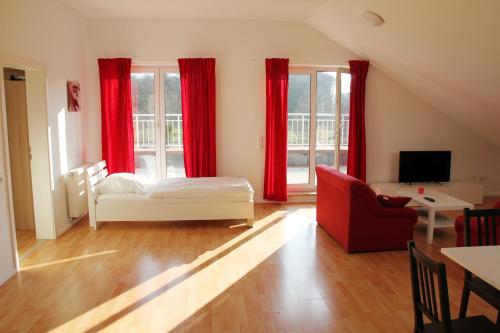 a bedroom with red curtains and a bed and a couch at Monteurwohnung Satzvey in Mechernich