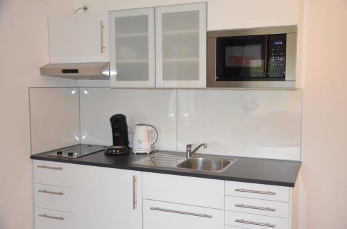 eine Küche mit weißen Schränken, einer Spüle und einer Mikrowelle in der Unterkunft Ankerplatz Kiel in Kiel