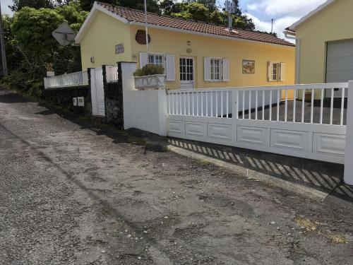 a house with a white fence next to a road at Adelaide House in Praia do Norte