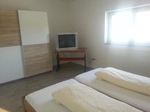 1 dormitorio con 2 camas y mesa con TV en Ferienwohnung Fasold, en Günzburg