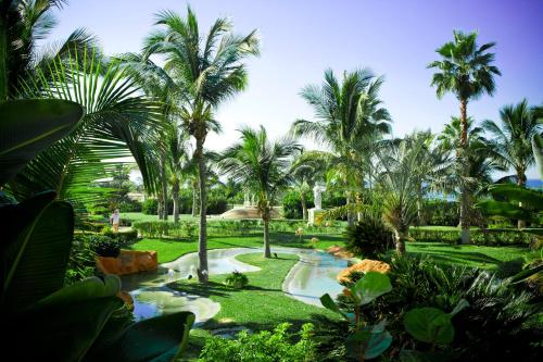 a garden with palm trees and a swimming pool at Pueblo Bonito Emerald Bay Resort & Spa - All Inclusive in Mazatlán