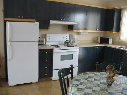 a kitchen with a white refrigerator and a table at Les Chalets au Bord de la Mer in Les Escoumins