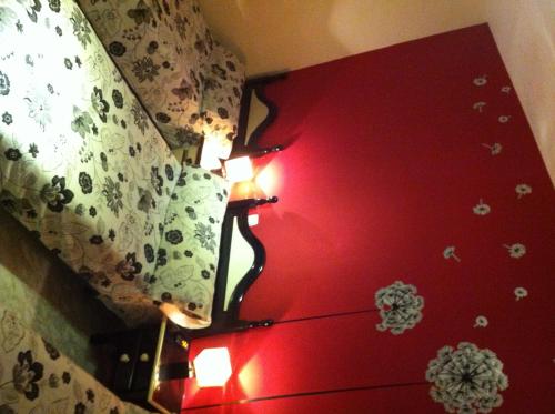 a bedroom with a red bed with two lights on it at Hostal Neptuno in Cáceres