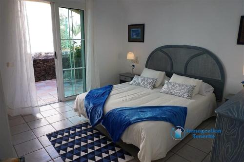 1 dormitorio con 1 cama grande con almohadas azules y blancas en Rocas del Mar Holiday en Costa del Silencio
