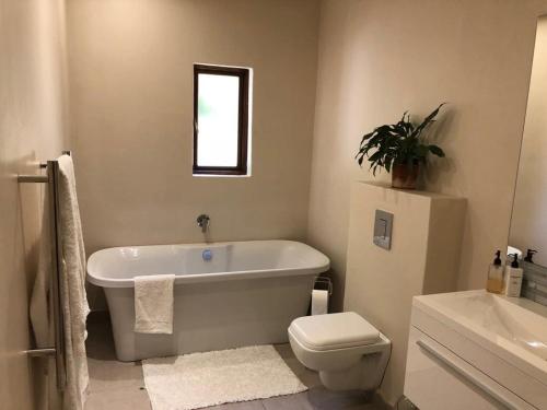 a bathroom with a tub and a toilet and a sink at Viettz Suite in Stellenbosch