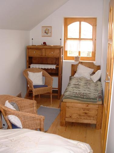 a bedroom with a bed and a chair and a window at Nyerges Lovasudvar in Cserépfalu