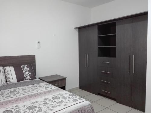 a bedroom with a bed and a wooden cabinet at MV Suites Suc. Capilla in Monterrey