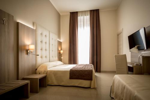 ジェノヴァにあるHotel Bel Soggiornoのベッド2台とテレビが備わるホテルルームです。