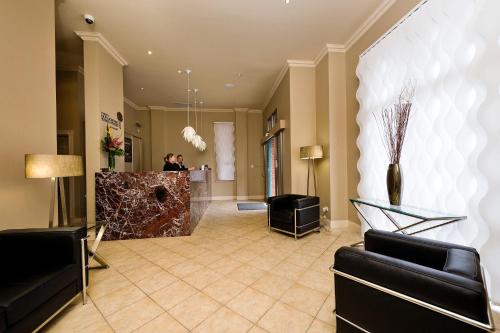 a lobby with black chairs and a reception desk at Majestic Old Lion Apartments in Adelaide
