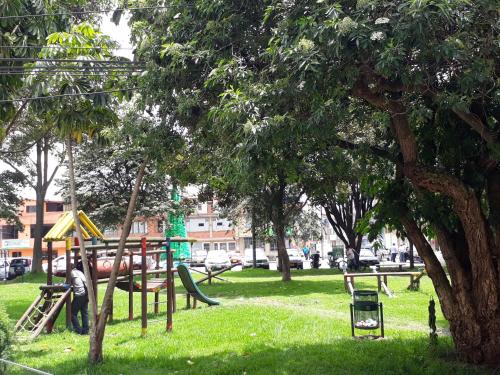 a park with a playground with a slide and trees at Aparta Hotel Victoria In in Bogotá