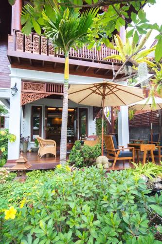 a house with a patio with chairs and an umbrella at Rich Garden House Hotel in Chiang Mai