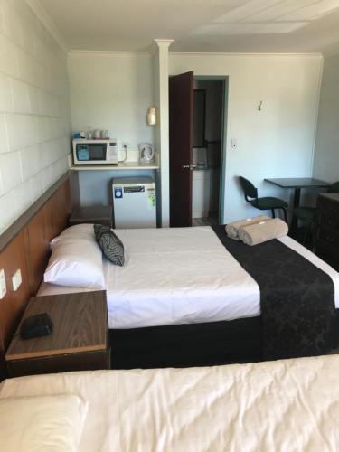 a hotel room with two beds and a kitchen at Longreach Most Central Motel in Longreach