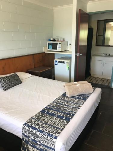 a bedroom with a bed with a microwave on the wall at Longreach Most Central Motel in Longreach