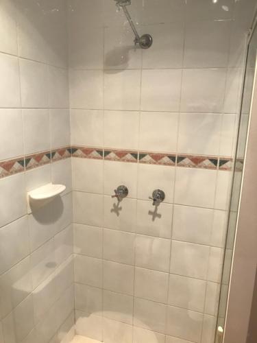 a bathroom with a shower with white tiles at Longreach Most Central Motel in Longreach