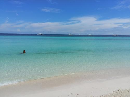 a person swimming in the ocean on a beach at Reggae Guesthouse in Panglao