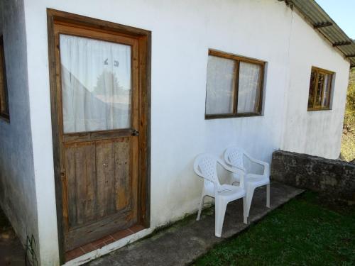 two chairs sitting outside of a house with a door at Posada Santa María in Mineral del Chico